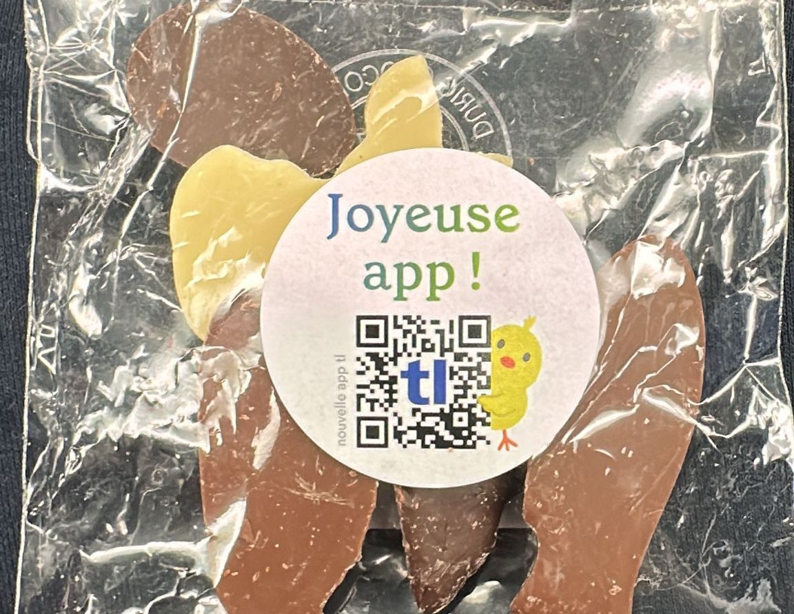 Sachet of animal -shaped chocolates with the inscription 'Joyeuse App!' On a printed sticker including a QR code and a chick drawing. Sachet of animal -shaped chocolates with the inscription 'Joyeuse App!' On a printed sticker including a QR code and a chick drawing.
