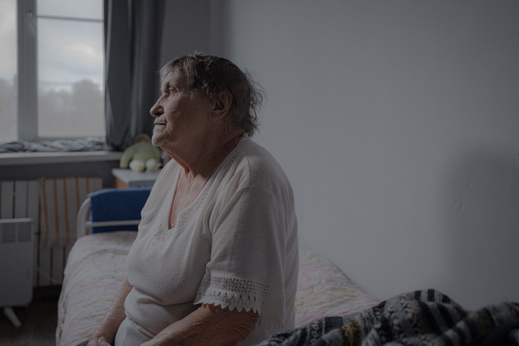 Zinaïda Guyrenko sits on her bed in the room she occupies in a refuge for seniors in Kharkiv, Ukraine, March 26, 2025