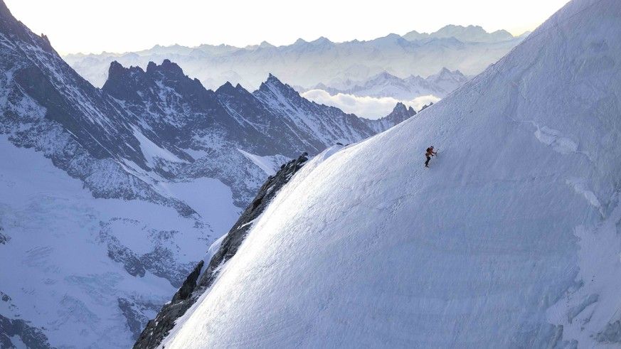 Nicolas Hojac climbs towards the summit ridge of the Eiger as the sun begins to rise in the distance on April 05, 2025.