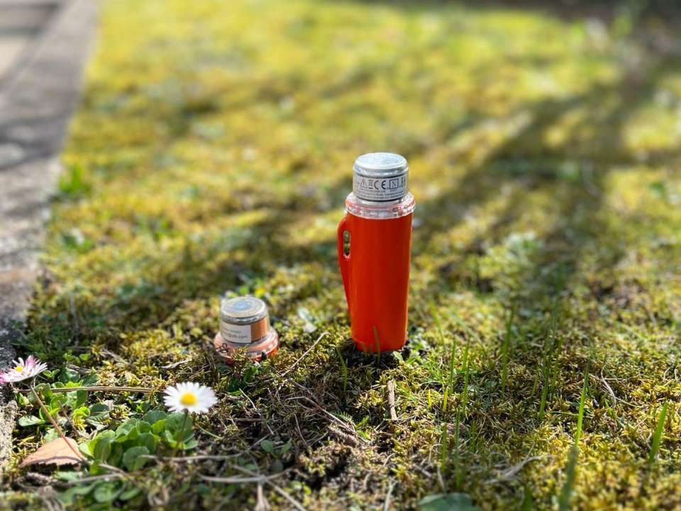 Two small bottles of sparkling water on a green lawn with white flowers in the background. Two small bottles of sparkling water on a green lawn with white flowers in the background.