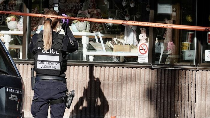 A policewoman photographs a window decorated for Easter, in front of a safety perimeter.