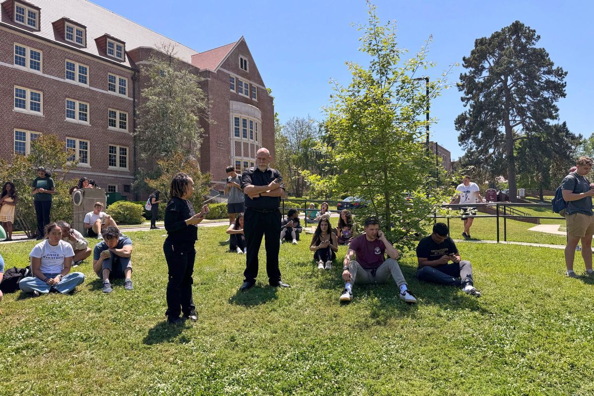 Students of Florida State University awaiting news during an active shooter incident on the campus in Tallahassee, with a building in the background. Students of Florida State University awaiting news during an active shooter incident on the campus in Tallahassee, with a building in the background.