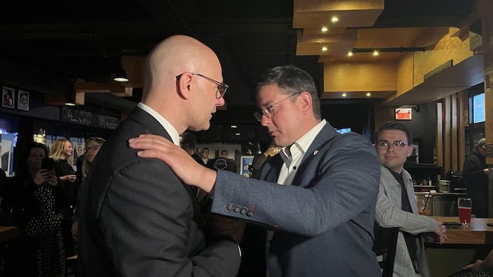 Two men shake hands.