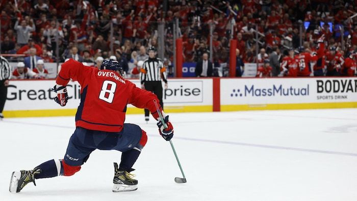 A hockey player celebrates a goal in front of cheers.