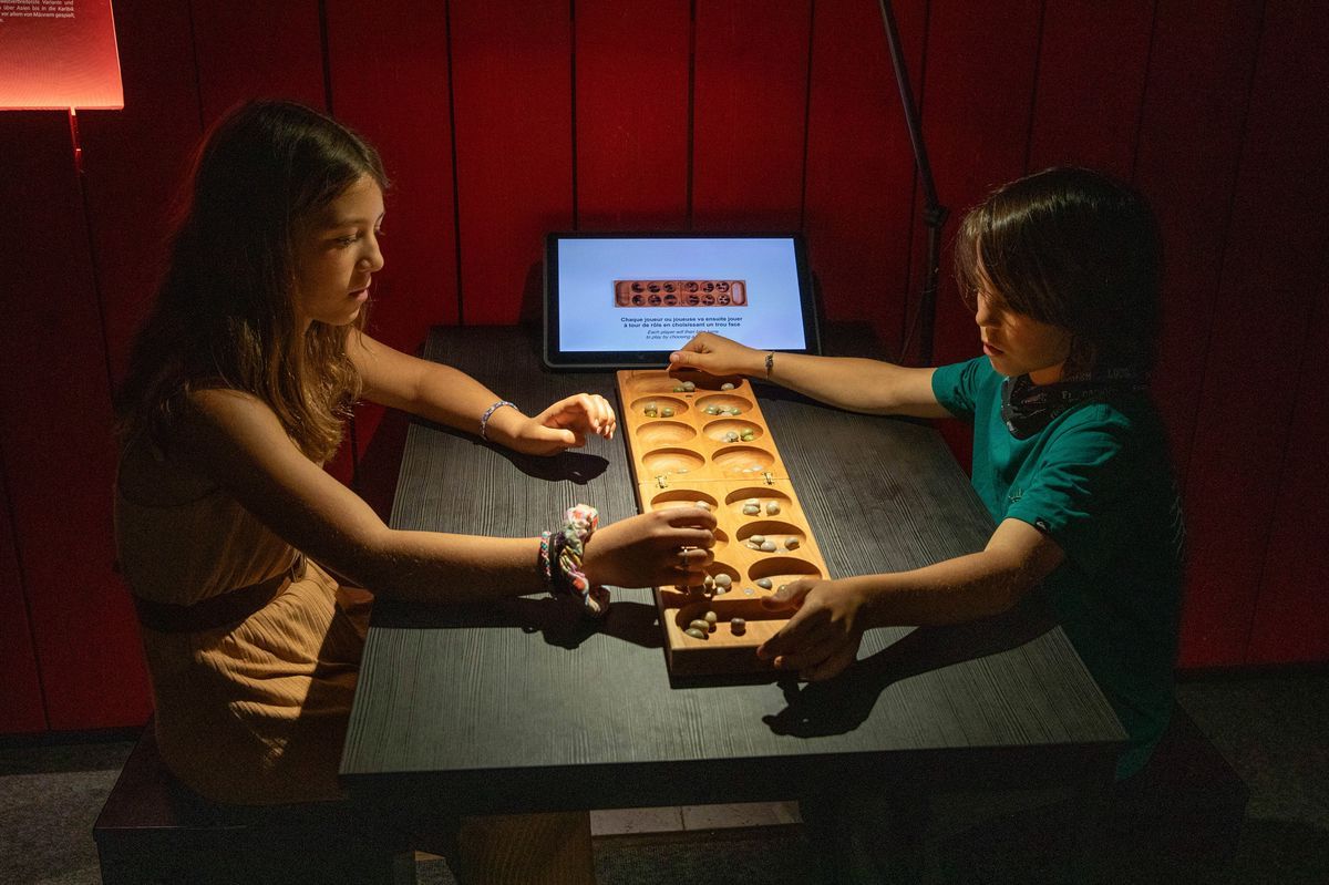 Two children play the game Awalé in an exhibition at the Swiss game museum, the Peilz tower, exploring environmental games and challenges. Two children play the game Awalé in an exhibition at the Swiss game museum, the Peilz tower, exploring environmental games and challenges.