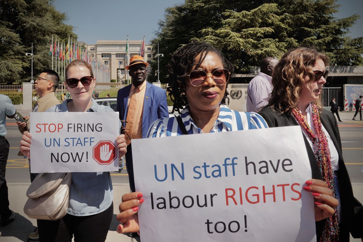 Protesters in front of a building sporting signs in support of the rights of UN employees, with slogans like 'a Staff have Labor Rights Too!' and 'Stop firing a staff now!'. Protesters in front of a building sporting signs in support of the rights of UN employees, with slogans like 'a Staff have Labor Rights Too!' and 'Stop firing a staff now!'.