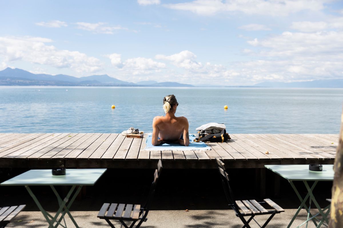 A woman takes advantage of the sun on the company's throw in Lausanne after a rainy weekend, with a view of Lake Geneva. A woman takes advantage of the sun on the company's throw in Lausanne after a rainy weekend, with a view of Lake Geneva.