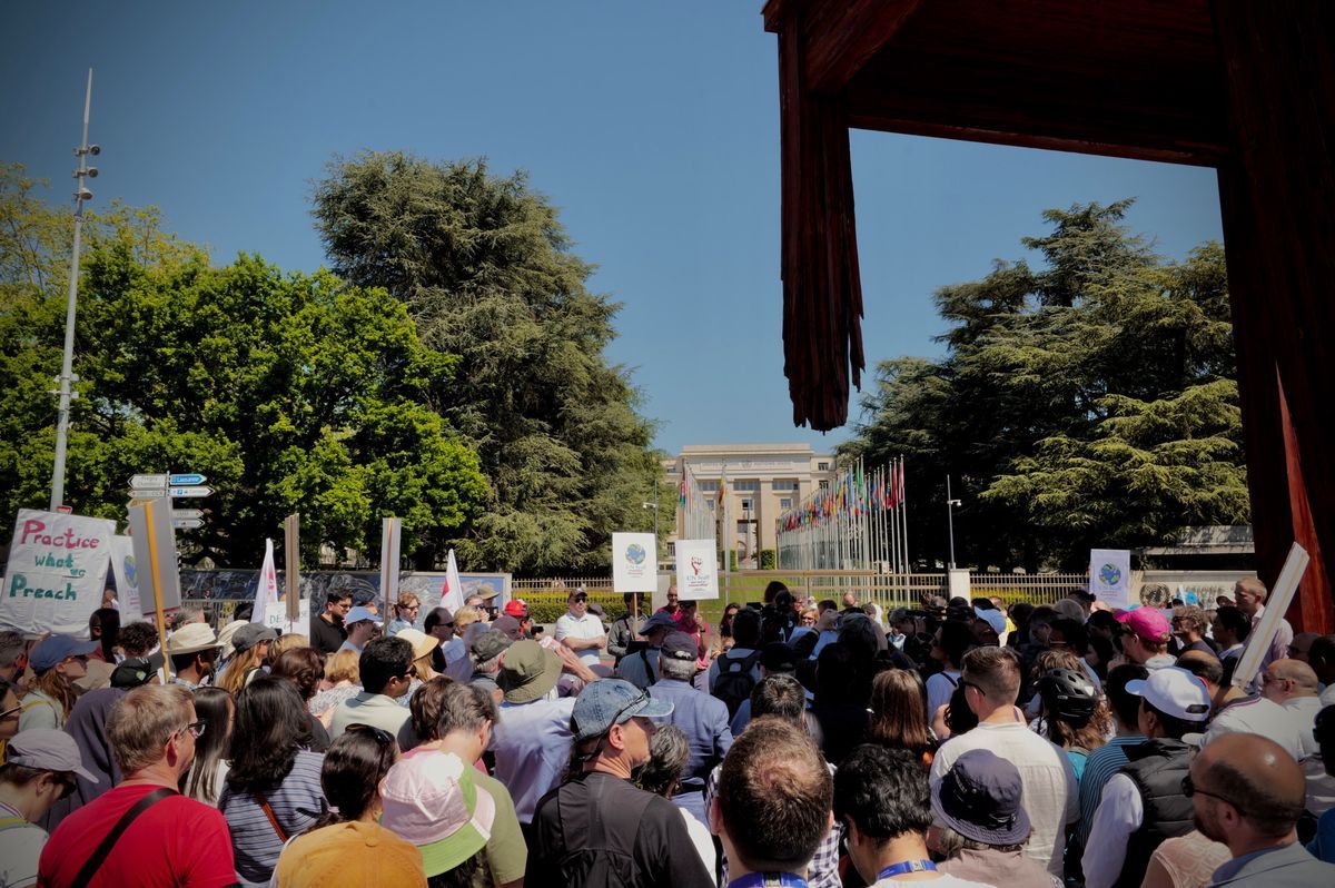 A crowd of demonstrators gathers in front of a government building with flags and signs demanding peace. A crowd of demonstrators gathers in front of a government building with flags and signs demanding peace.