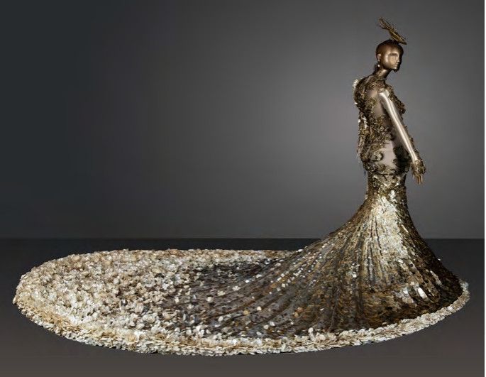Mannequin carrying a sparkling golden dress with a long train, on a gray background. Mannequin carrying a sparkling golden dress with a long train, on a gray background.