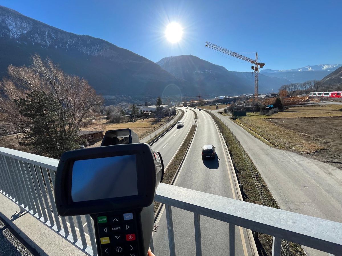 Sunny road with a speed radar, mountains in the background, and a construction crane on the right. Sunny road with a speed radar, mountains in the background, and a construction crane on the right.