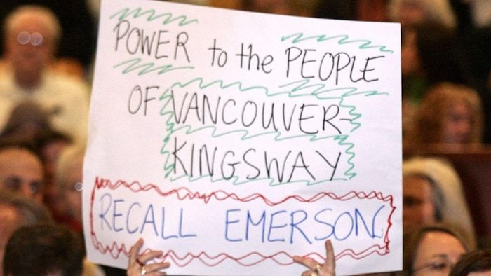 A photo shows an unhappy voter who holds a poster denouncing the appointment of the Liberal MP David Emerson within the Cabinet of the Conservative Government of Stephen Harper.