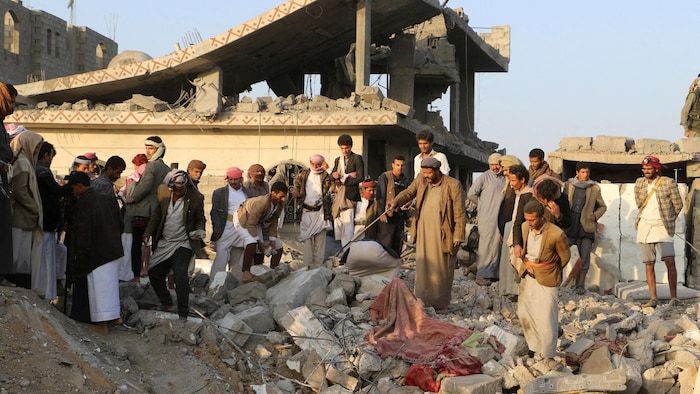 People gather on the rubble of a house.