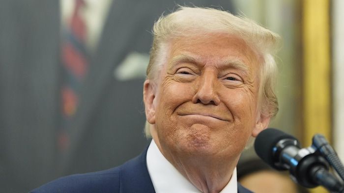 Donald Trump smiles in front of a microphone.