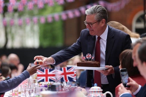 epa12075513 British Prime Minister Keir Starmer hands out cakes at a street party on Downing Street to commemorate the 80th anniversary of Victory in Europe (VE Day) in London, Britain, 05 May 2025. E ...