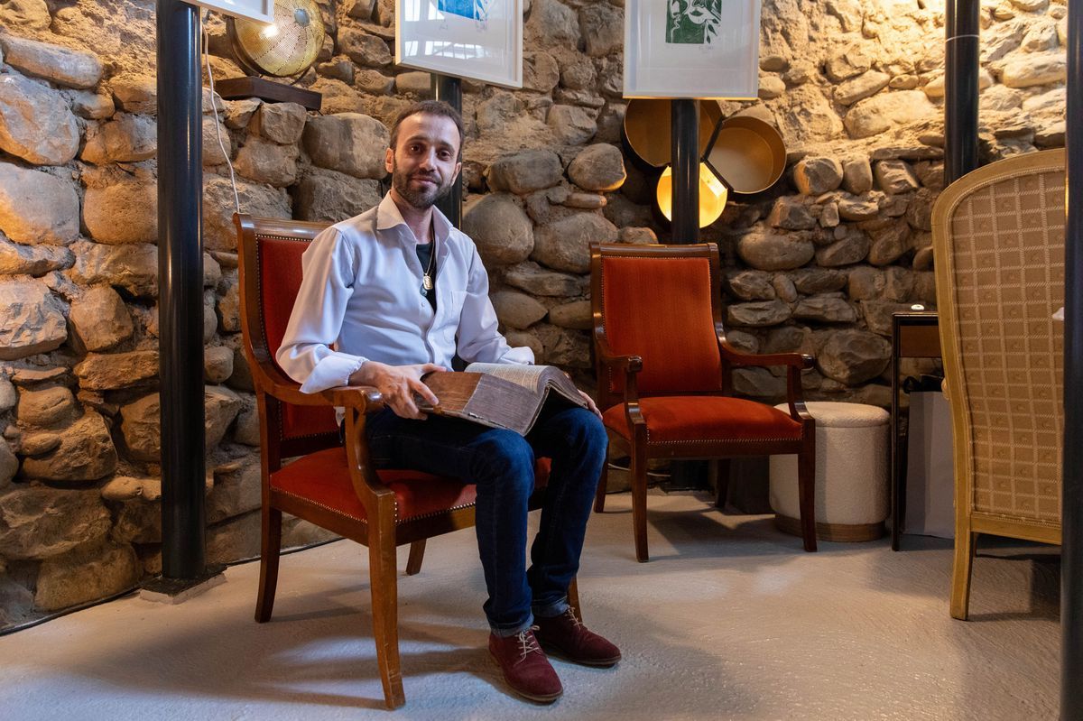 Romain Maceli seated in his art gallery in Vevey, located in the remains of a 15th century tower, surrounded by exposed stones and old furniture. Romain Maceli seated in his art gallery in Vevey, located in the remains of a 15th century tower, surrounded by exposed stones and old furniture.