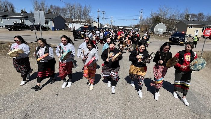 Eight women open walking by playing the traditional drum. They also wear traditional ribbon skirts.