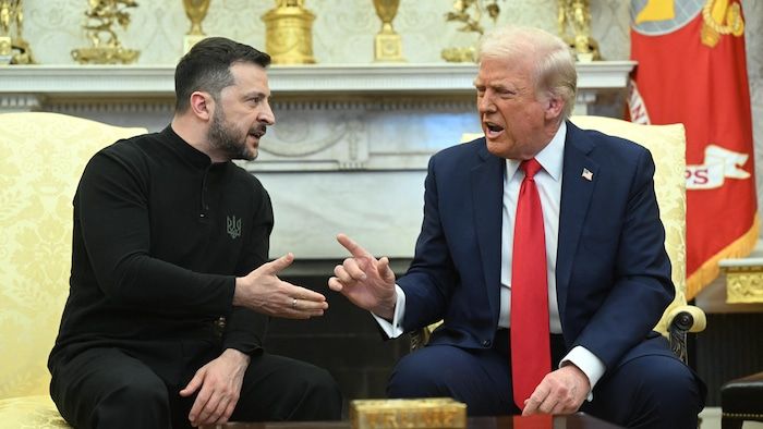 The two men are seated and argue.