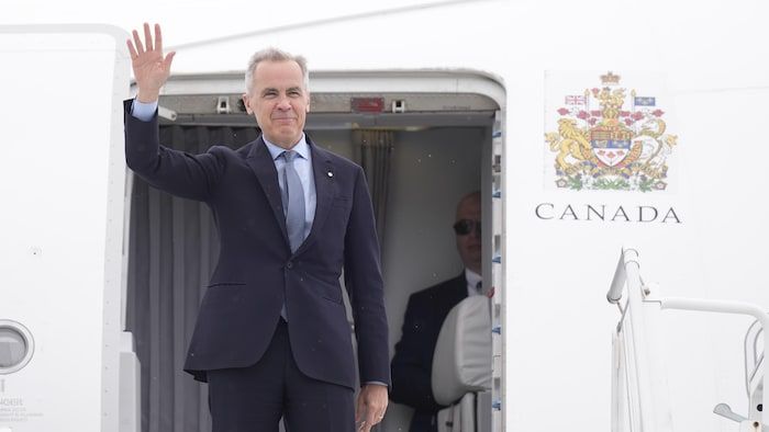 Mark Carney takes out and sends his hand to the entrance to an airplane.