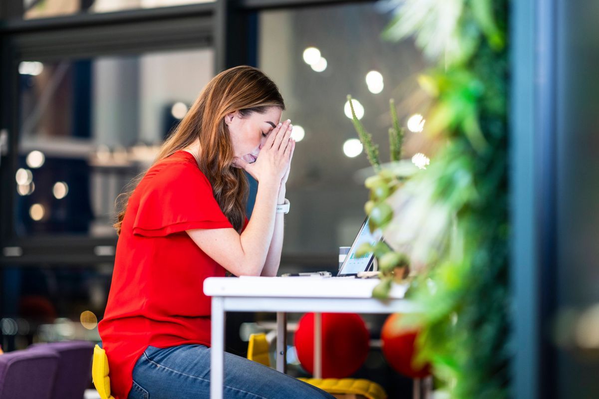 Stressed businesswoman sitting near a laptop in an office. Stressed businesswoman sitting near a laptop in an office.