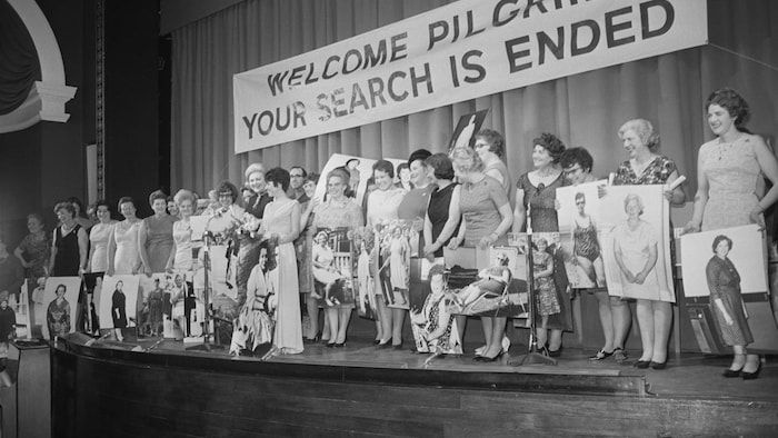 On a stage, women are in front of them in giant format photos.