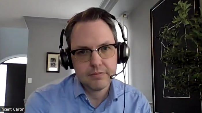 Vincent Caron in an interview and sitting in a living room with a listening helmet with a microphone.