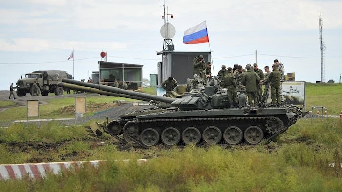 Russian soldiers standing on a tank.