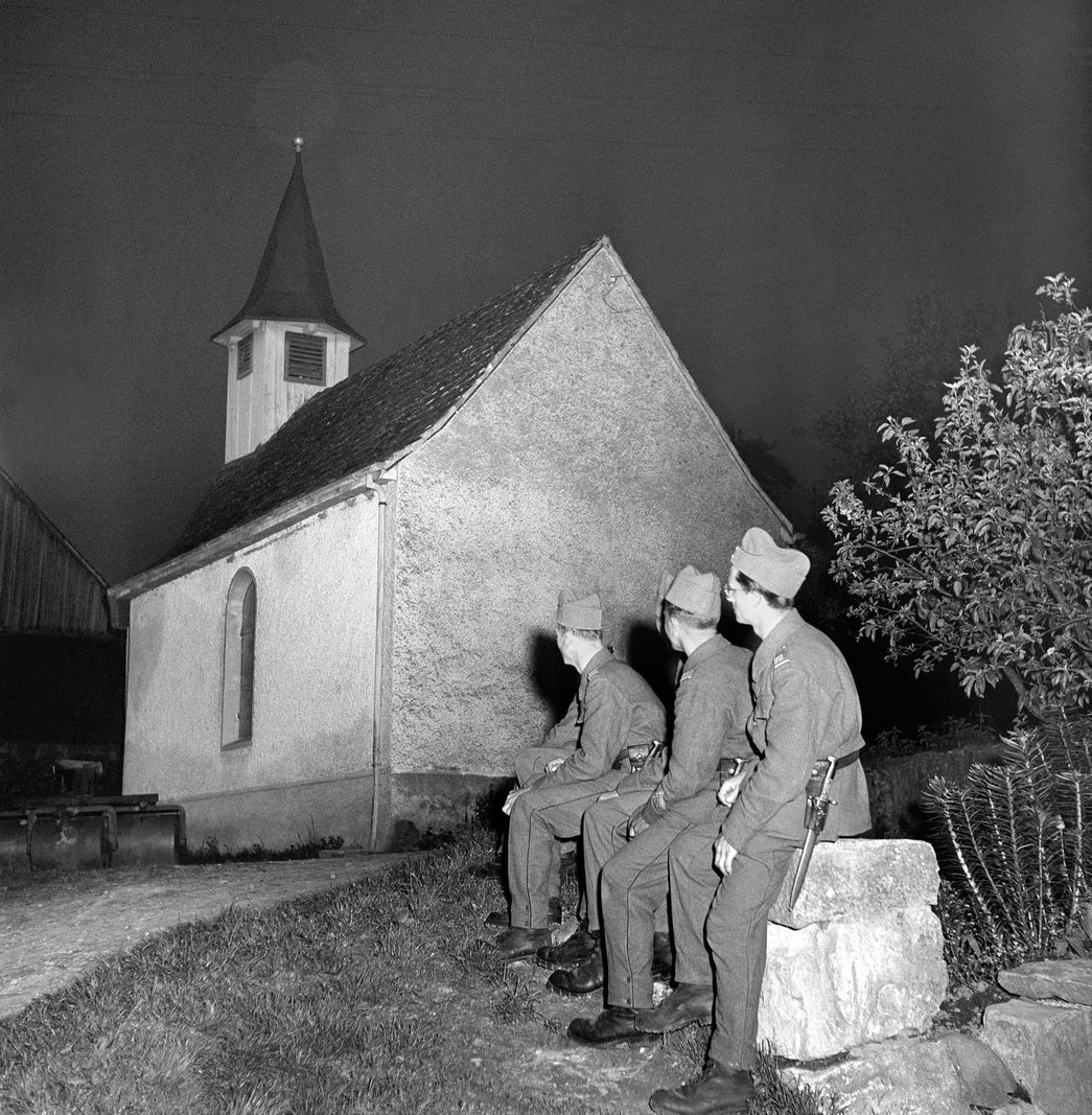 Soldiers sit in front of a small church in a village in the canton of Aargau, Switzerland, and listen to the bell ringing to celebrate the end of the war on May 8, 1945. Soldiers sit in front of a small church in a village in the canton of Aargau, Switzerland, and listen to the bell ringing to celebrate the end of the war on May 8, 1945.