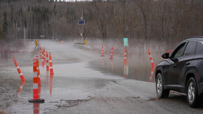 A car rolls on a partly flooded path.