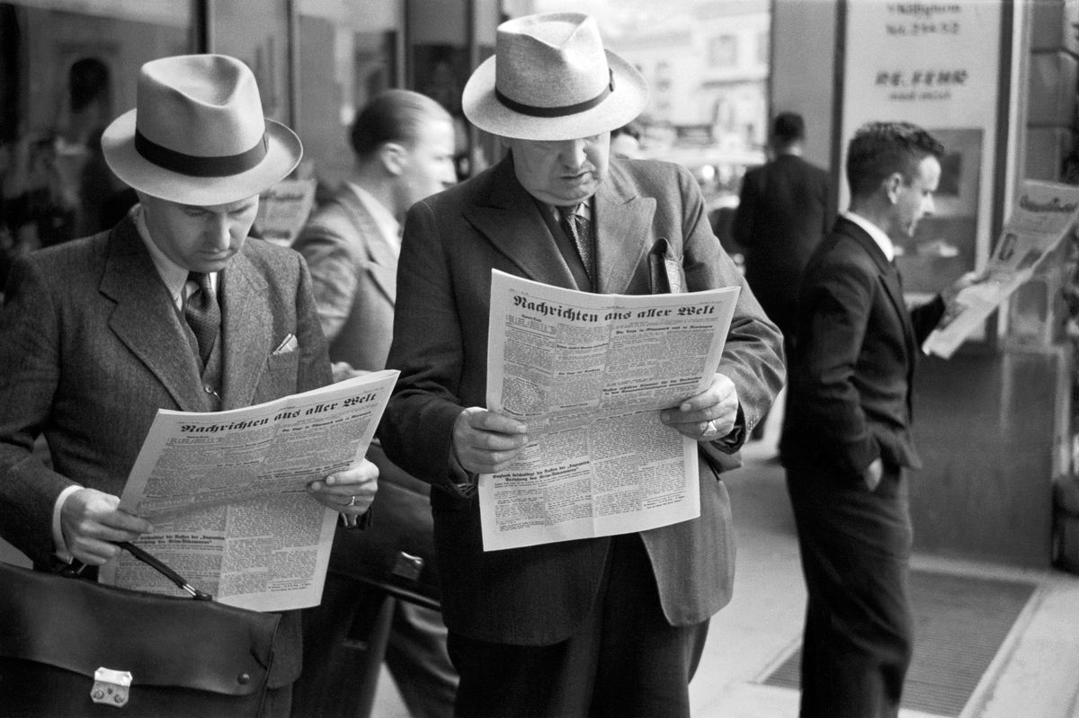 Men in suits and guardians read newspapers while standing on the day of the end of the war in Bern, Switzerland, May 8, 1945. The scene shows the quiet atmosphere in the city. Men in suits and guardians read newspapers while standing on the day of the end of the war in Bern, Switzerland, May 8, 1945. The scene shows the quiet atmosphere in the city.