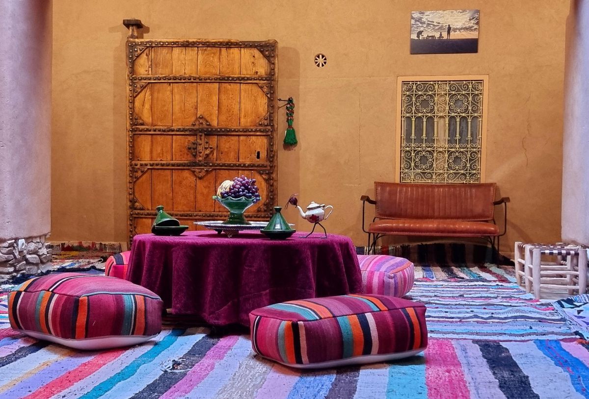 Traditional Moroccan lounge area with colorful cushions, round coffee table and wooden wall decor. Traditional Moroccan lounge area with colorful cushions, round coffee table and wooden wall decor.