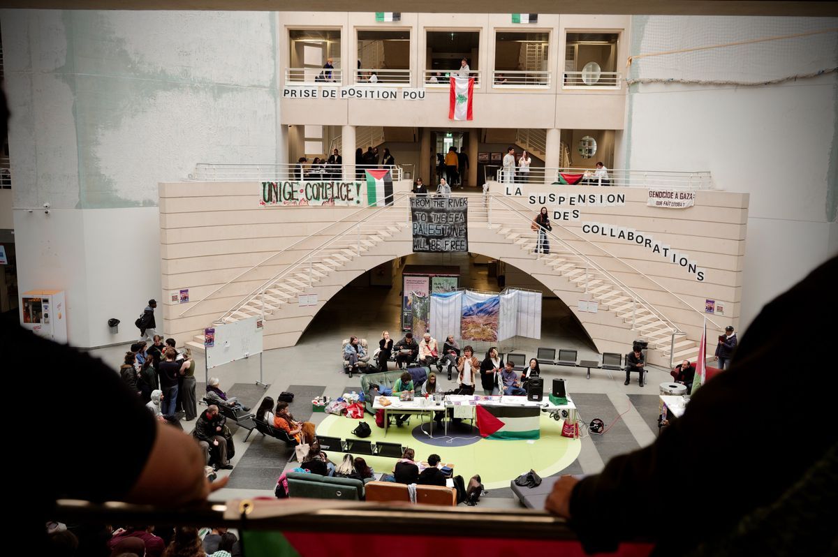 Public gathering in a building with stairs, banners with political messages and people sitting around tables. Public gathering in a building with stairs, banners with political messages and people sitting around tables.