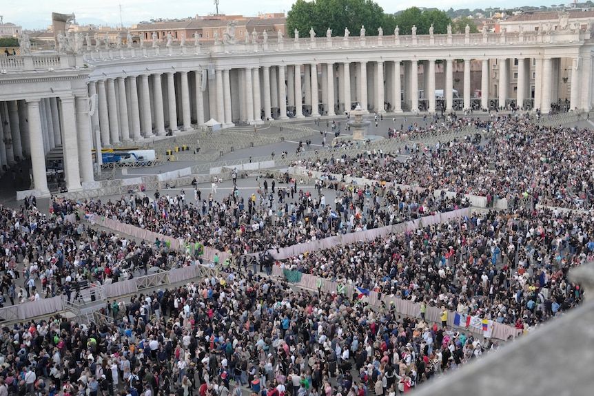 Large crowds of people gathered in quadrants of St Peter's Square, seen from atop the Vatican