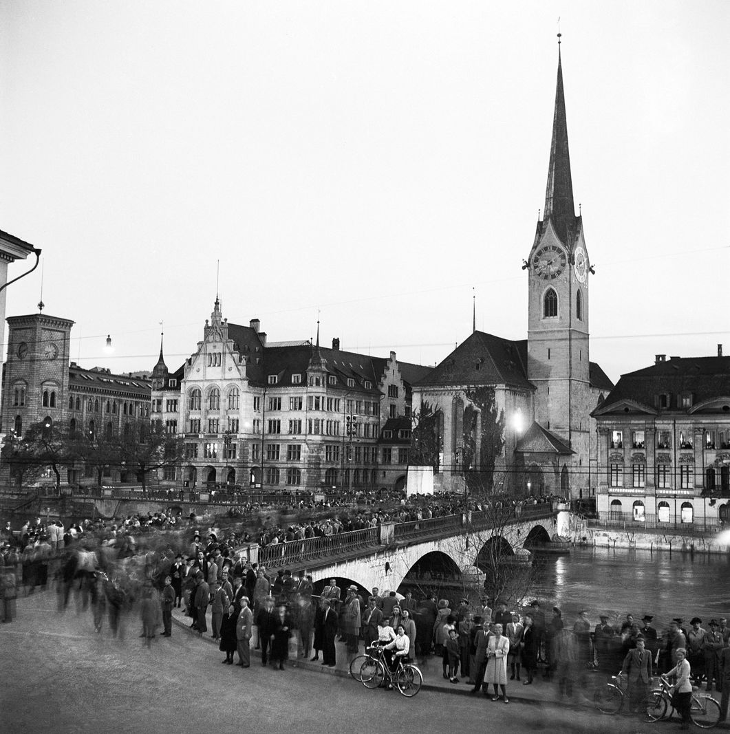 The Münsterbruecke in Zurich on May 8, 1945, with crowds that celebrate the end of the war. The Fraumünsterkirche in the background. The Münsterbruecke in Zurich on May 8, 1945, with crowds that celebrate the end of the war. The Fraumünsterkirche in the background.