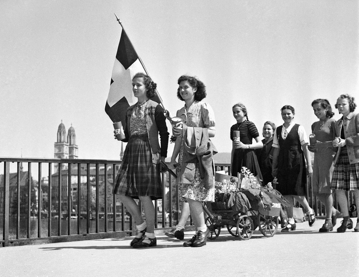 Girls with a Swiss flag and decorated ladder trolleys cross the Quai bridge in Zurich on May 8, 1945. Girls with a Swiss flag and decorated ladder trolleys cross the Quai bridge in Zurich on May 8, 1945.