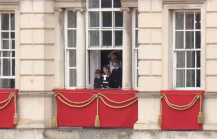Kate Middleton, behind a balcony window with her children