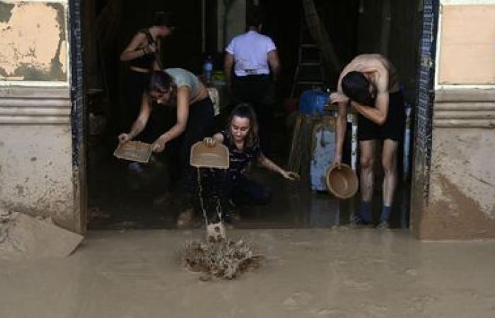 a crowd of volunteers are busy cleaning up the disaster-stricken towns near Valencia