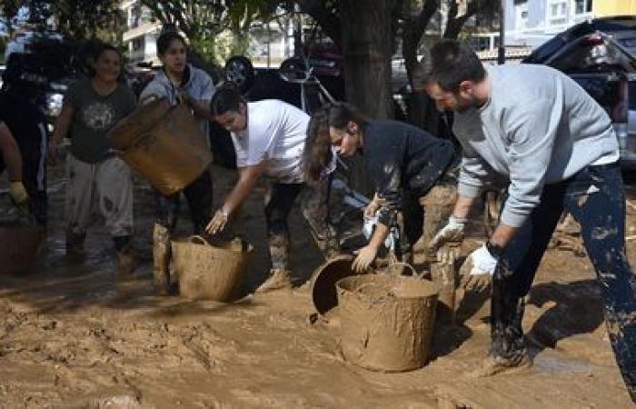 a crowd of volunteers are busy cleaning up the disaster-stricken towns near Valencia