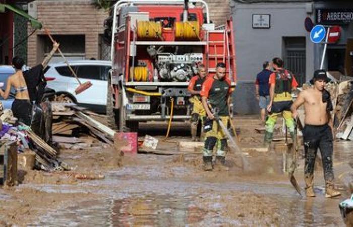 a crowd of volunteers are busy cleaning up the disaster-stricken towns near Valencia