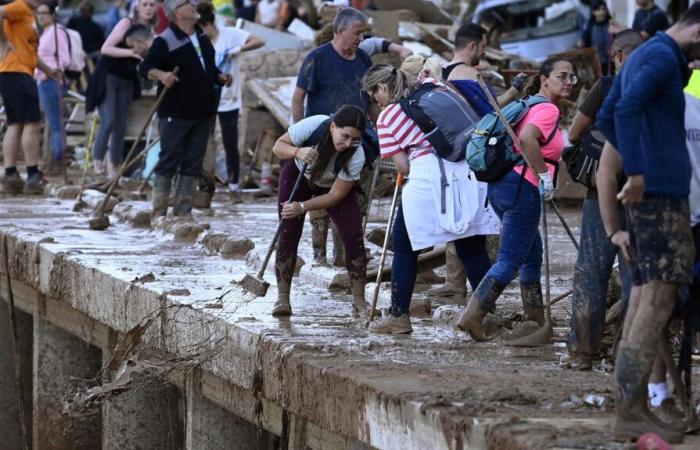 a crowd of volunteers are busy cleaning up the disaster-stricken towns near Valencia