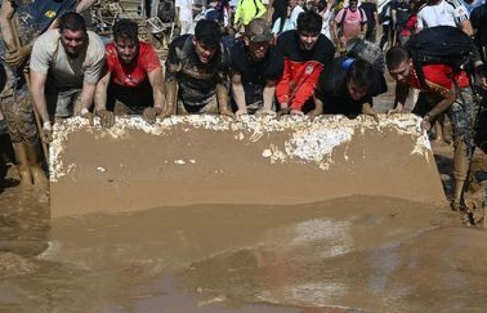 a crowd of volunteers are busy cleaning up the disaster-stricken towns near Valencia