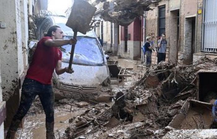 a crowd of volunteers are busy cleaning up the disaster-stricken towns near Valencia