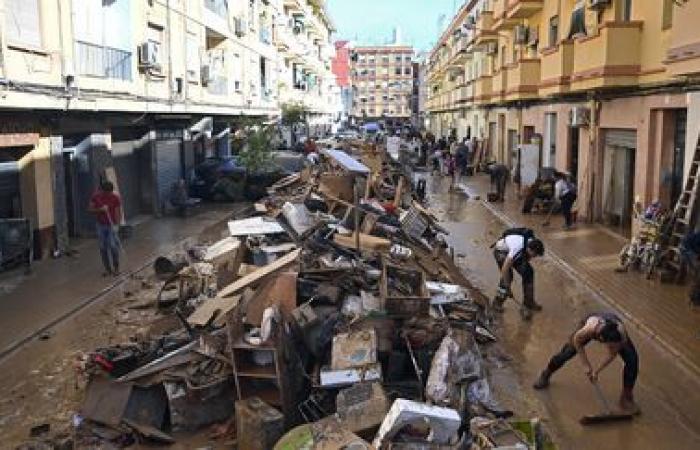 a crowd of volunteers are busy cleaning up the disaster-stricken towns near Valencia