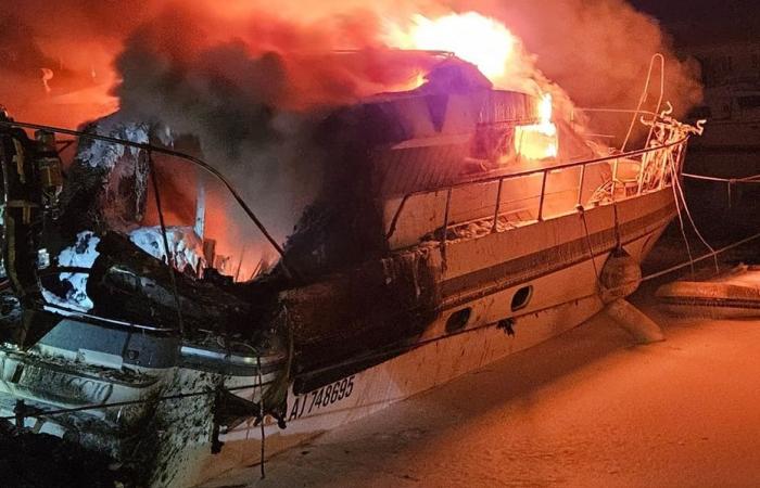 Impressive fire on a boat in the middle of the night in a port, containment operations carried out to avoid any risk of pollution