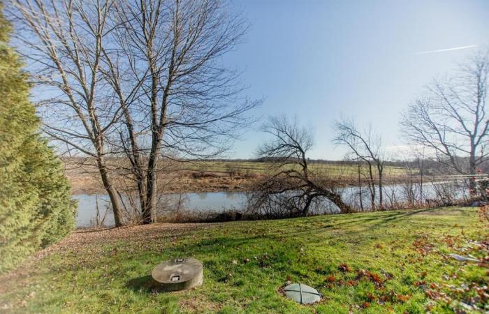 Elegant cottage bordering a body of water against a backdrop of rural tranquility